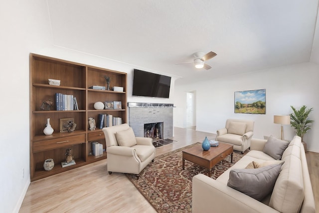 living room with ceiling fan, light hardwood / wood-style floors, and a fireplace