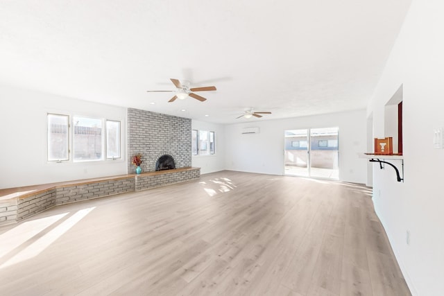 unfurnished living room with ceiling fan, a healthy amount of sunlight, a fireplace, and light hardwood / wood-style flooring