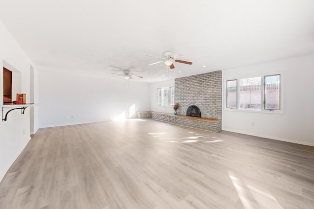 unfurnished living room with ceiling fan, light hardwood / wood-style floors, and a brick fireplace