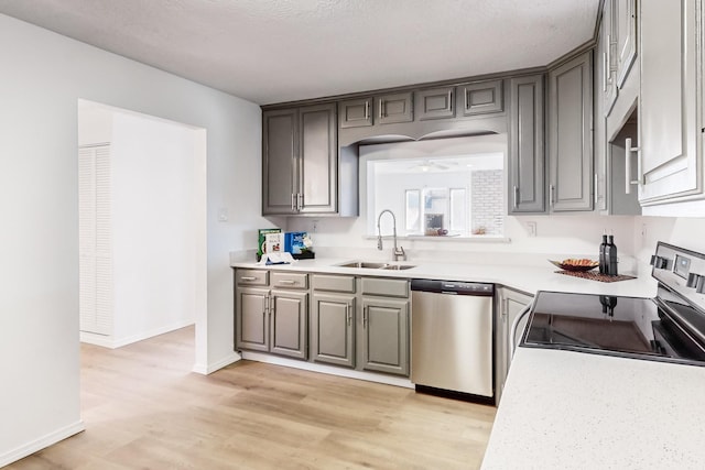 kitchen featuring a textured ceiling, stainless steel appliances, sink, light hardwood / wood-style flooring, and gray cabinets