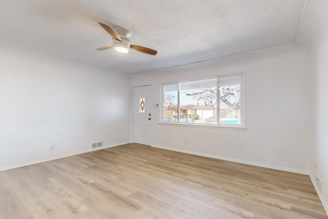 empty room featuring ceiling fan, light hardwood / wood-style flooring, and a textured ceiling