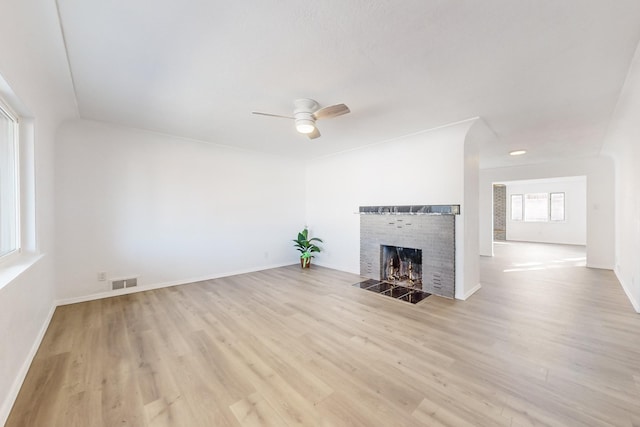 unfurnished living room with light hardwood / wood-style floors, a brick fireplace, and ceiling fan