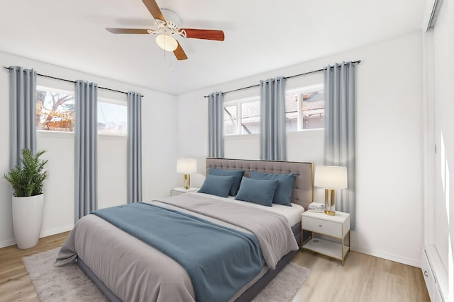 bedroom with ceiling fan, multiple windows, and light hardwood / wood-style flooring