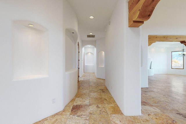 corridor with visible vents, arched walkways, stone tile flooring, and recessed lighting