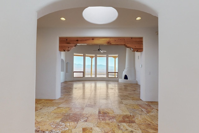 unfurnished room featuring stone finish flooring, arched walkways, and recessed lighting