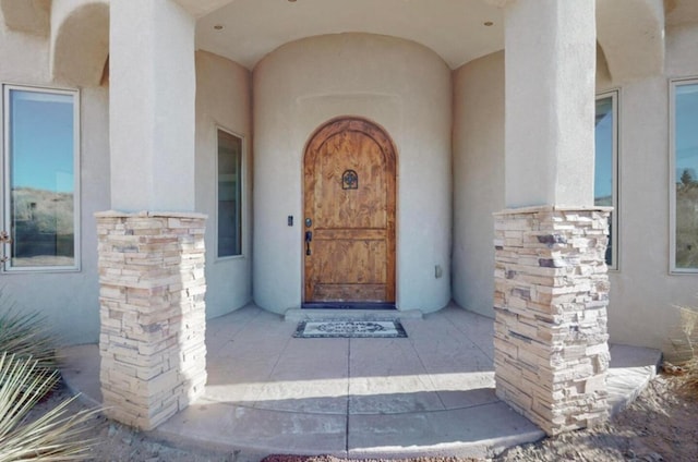 view of exterior entry featuring stone siding and stucco siding