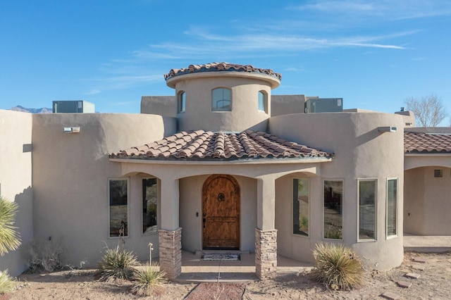 mediterranean / spanish house featuring a tile roof and stucco siding