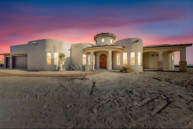 view of front of house featuring a garage, concrete driveway, a tile roof, and stucco siding