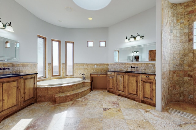 bathroom featuring a sink, tiled shower, tasteful backsplash, two vanities, and a garden tub