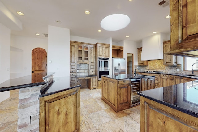 kitchen with a kitchen island with sink, beverage cooler, visible vents, appliances with stainless steel finishes, and decorative backsplash