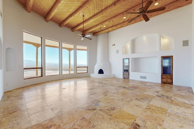 unfurnished living room featuring visible vents, a towering ceiling, wood ceiling, ceiling fan, and beamed ceiling