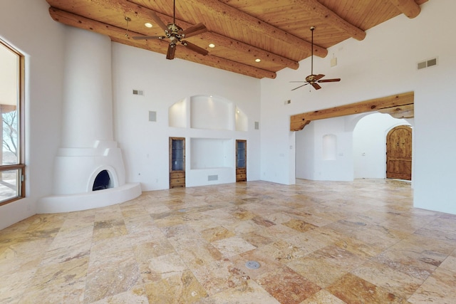 unfurnished living room featuring a large fireplace, visible vents, a ceiling fan, wood ceiling, and beam ceiling