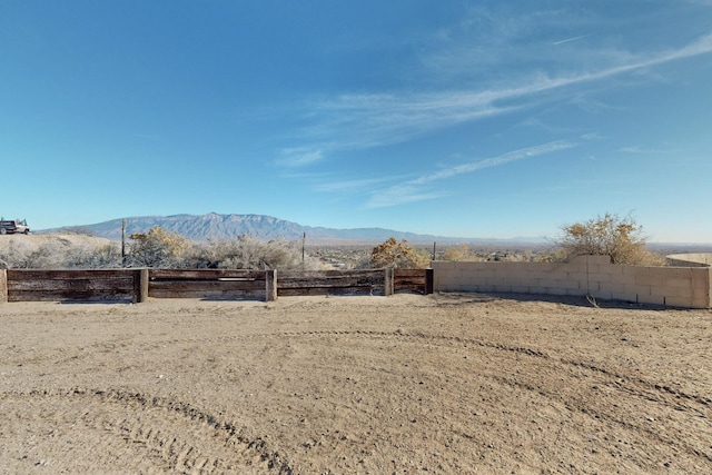 view of yard featuring fence, a mountain view, and a rural view