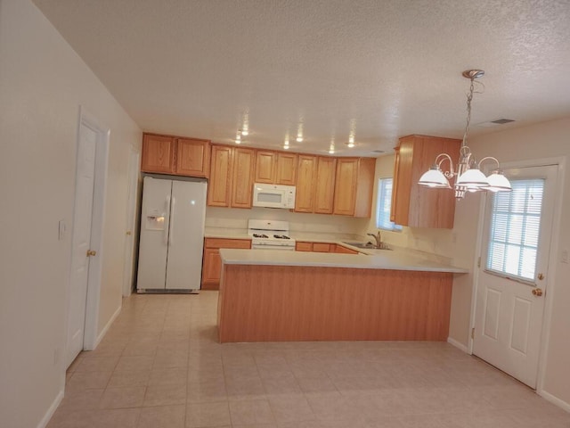 kitchen with sink, an inviting chandelier, kitchen peninsula, pendant lighting, and white appliances