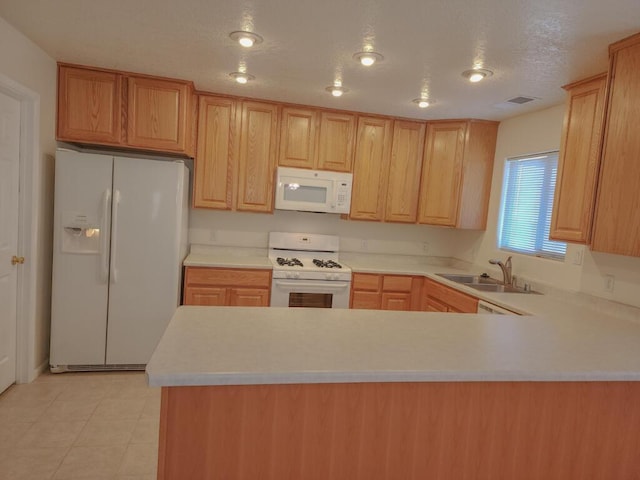 kitchen with kitchen peninsula, sink, white appliances, and light brown cabinets