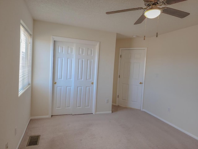 unfurnished bedroom featuring a textured ceiling, ceiling fan, light carpet, and a closet