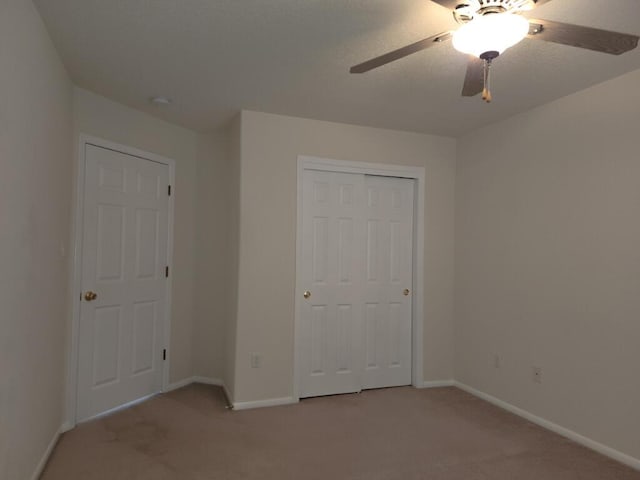 unfurnished bedroom featuring ceiling fan, a closet, and light colored carpet