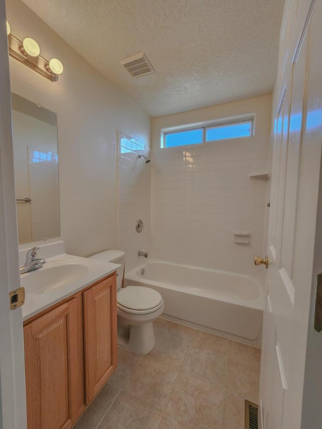 full bathroom with tile patterned flooring, vanity, a textured ceiling, and tiled shower / bath