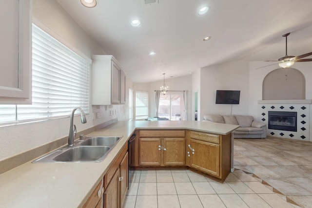 kitchen with sink, vaulted ceiling, black dishwasher, light tile patterned flooring, and kitchen peninsula