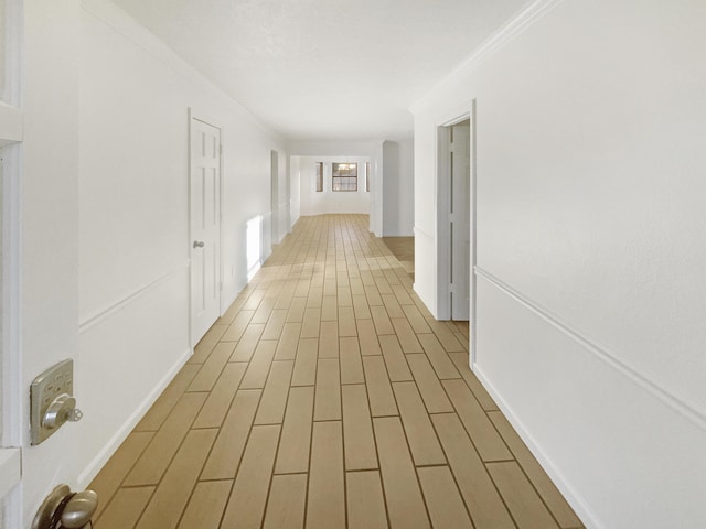 hallway featuring crown molding and light hardwood / wood-style floors