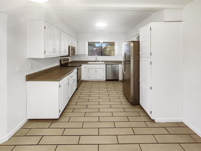 kitchen with light tile patterned flooring, appliances with stainless steel finishes, white cabinetry, and sink