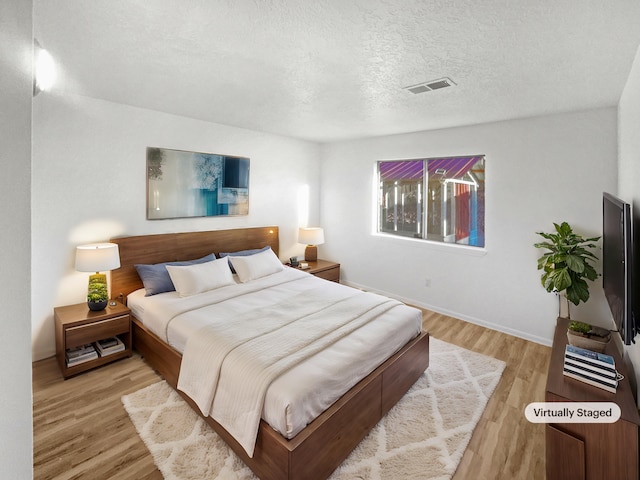 bedroom with a textured ceiling and light hardwood / wood-style flooring