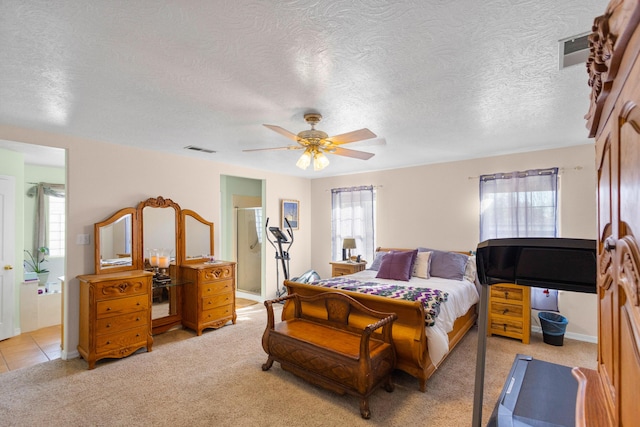 carpeted bedroom with a textured ceiling, connected bathroom, and ceiling fan