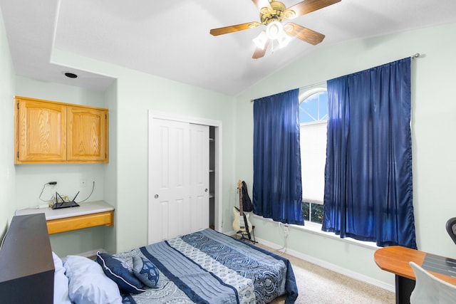 carpeted bedroom with ceiling fan, a closet, and vaulted ceiling