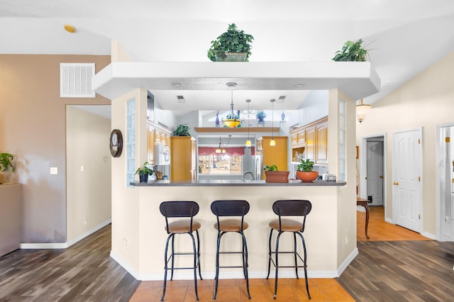 kitchen featuring pendant lighting, a kitchen bar, dark hardwood / wood-style flooring, and kitchen peninsula