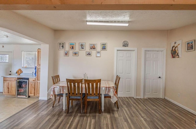 dining room with dark hardwood / wood-style flooring, beverage cooler, and a textured ceiling