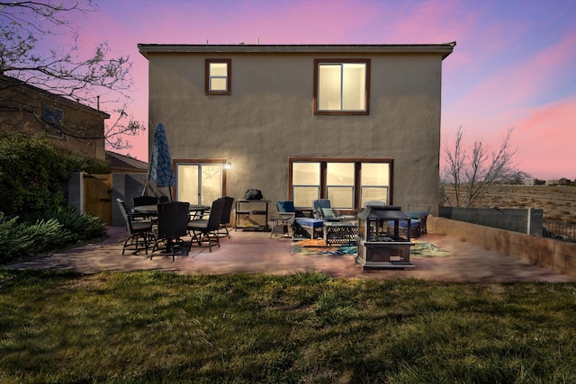 back house at dusk with a yard and a patio