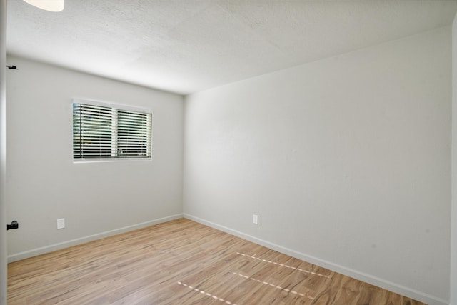 unfurnished room with a textured ceiling and light hardwood / wood-style flooring