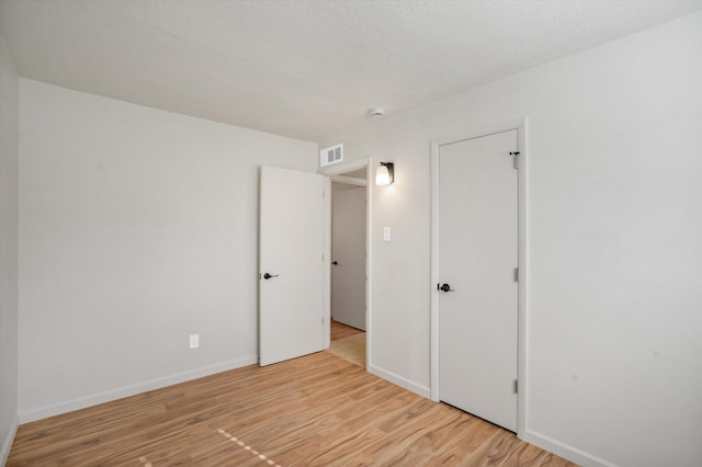 unfurnished bedroom with light hardwood / wood-style floors and a textured ceiling