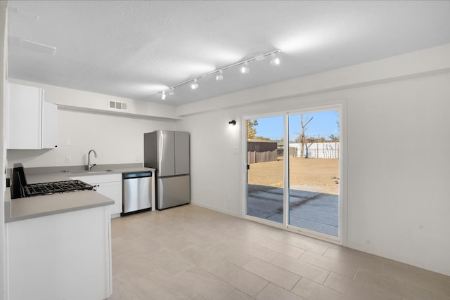 kitchen with sink, a textured ceiling, track lighting, stainless steel appliances, and white cabinets