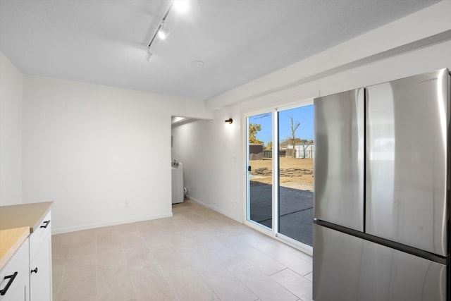 interior space featuring white cabinetry, stainless steel fridge, and rail lighting