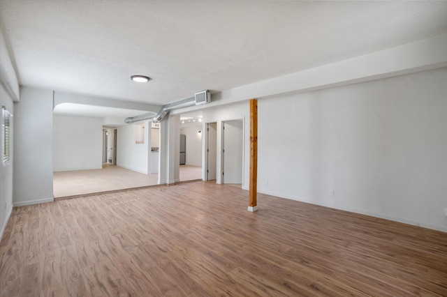 basement with fridge and light hardwood / wood-style flooring