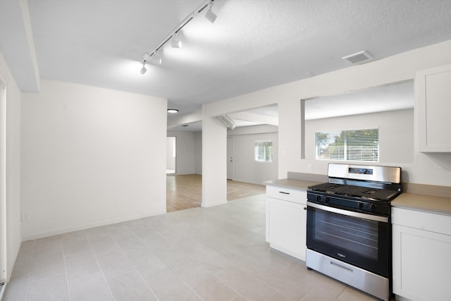 kitchen with stainless steel range with gas stovetop, a textured ceiling, and white cabinets