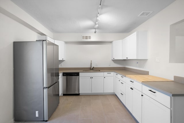 kitchen featuring stainless steel appliances, white cabinetry, sink, and a textured ceiling