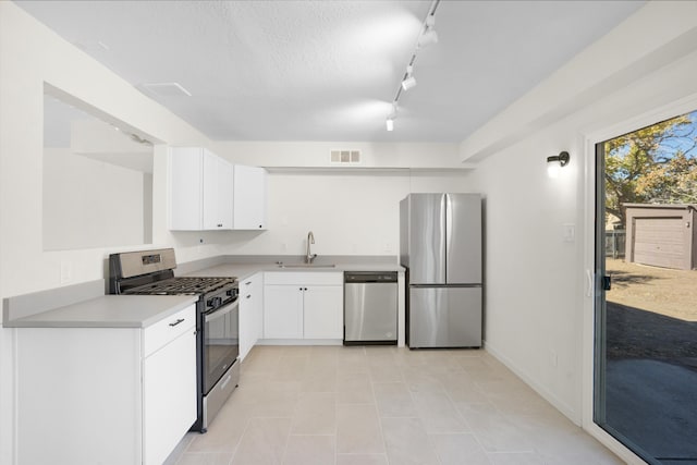 kitchen with appliances with stainless steel finishes, sink, white cabinets, and a textured ceiling