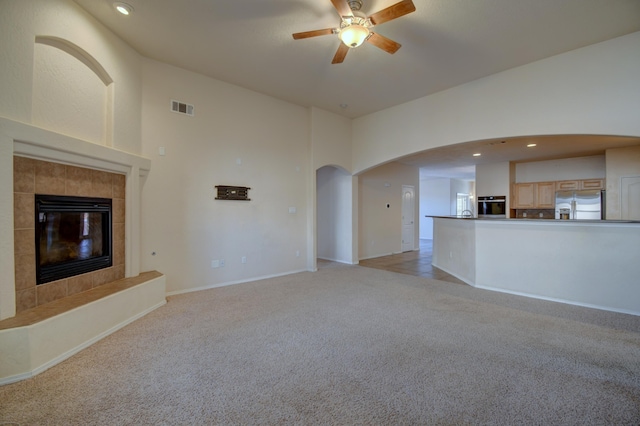 unfurnished living room with ceiling fan, light carpet, and a tile fireplace