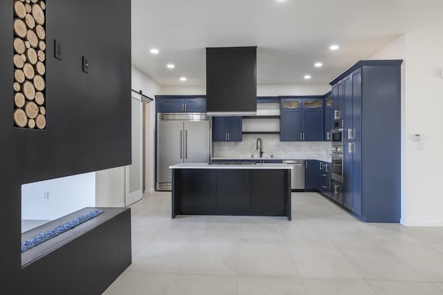 kitchen featuring a barn door, blue cabinetry, appliances with stainless steel finishes, tasteful backsplash, and a kitchen island