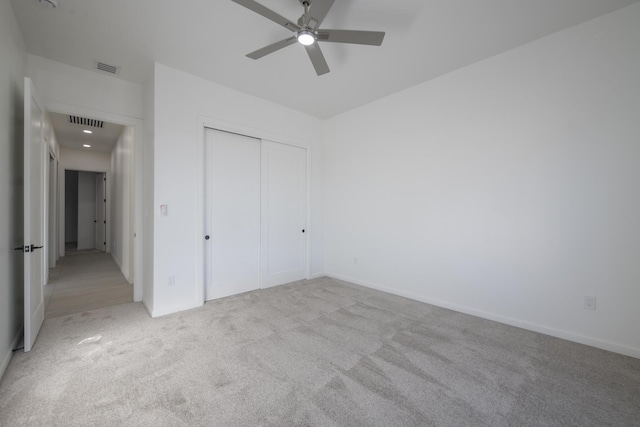 unfurnished bedroom featuring light carpet, a closet, and ceiling fan