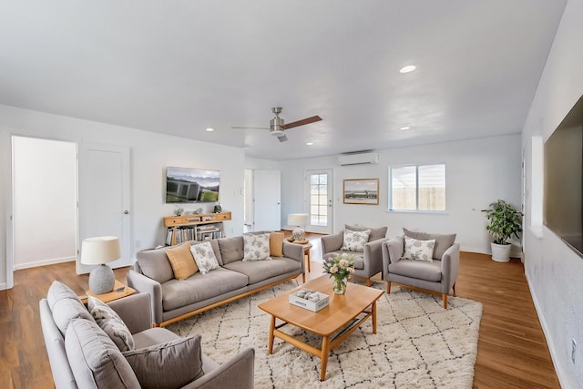 living room featuring light hardwood / wood-style floors, an AC wall unit, and ceiling fan