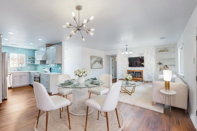 dining area featuring a fireplace, hardwood / wood-style flooring, an inviting chandelier, and sink