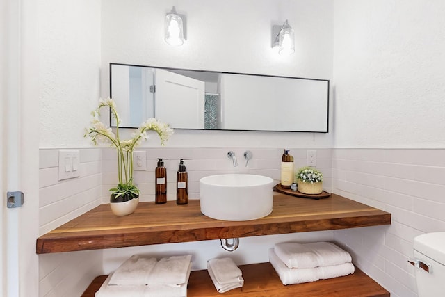 bathroom featuring sink, tile walls, and toilet