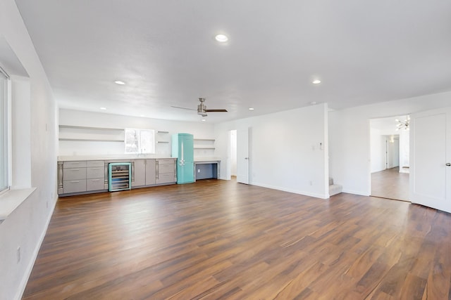 unfurnished living room with ceiling fan, dark wood-type flooring, and beverage cooler