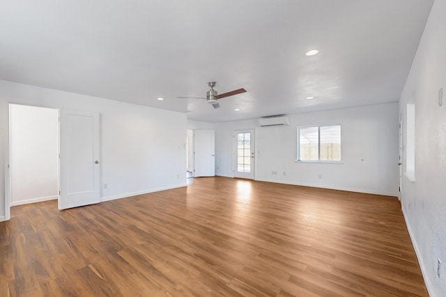 unfurnished room with an AC wall unit, ceiling fan, and hardwood / wood-style floors