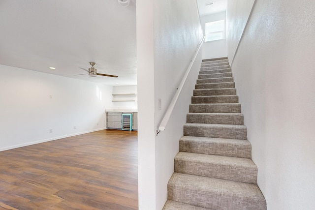 staircase with wood-type flooring, wine cooler, and ceiling fan