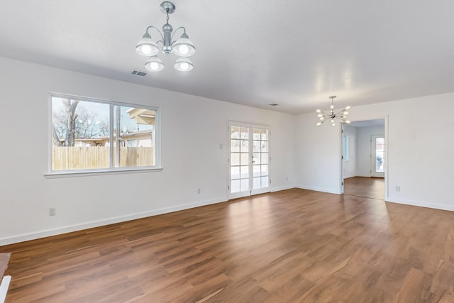 spare room with wood-type flooring and an inviting chandelier