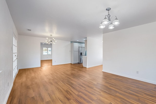 unfurnished living room featuring hardwood / wood-style floors and a notable chandelier